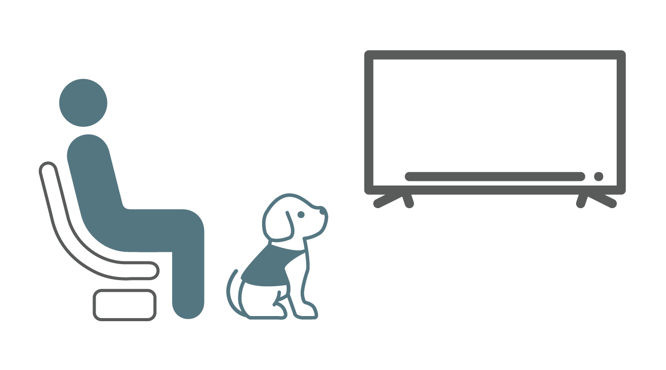 A person in a recliner with a service dog watching television.